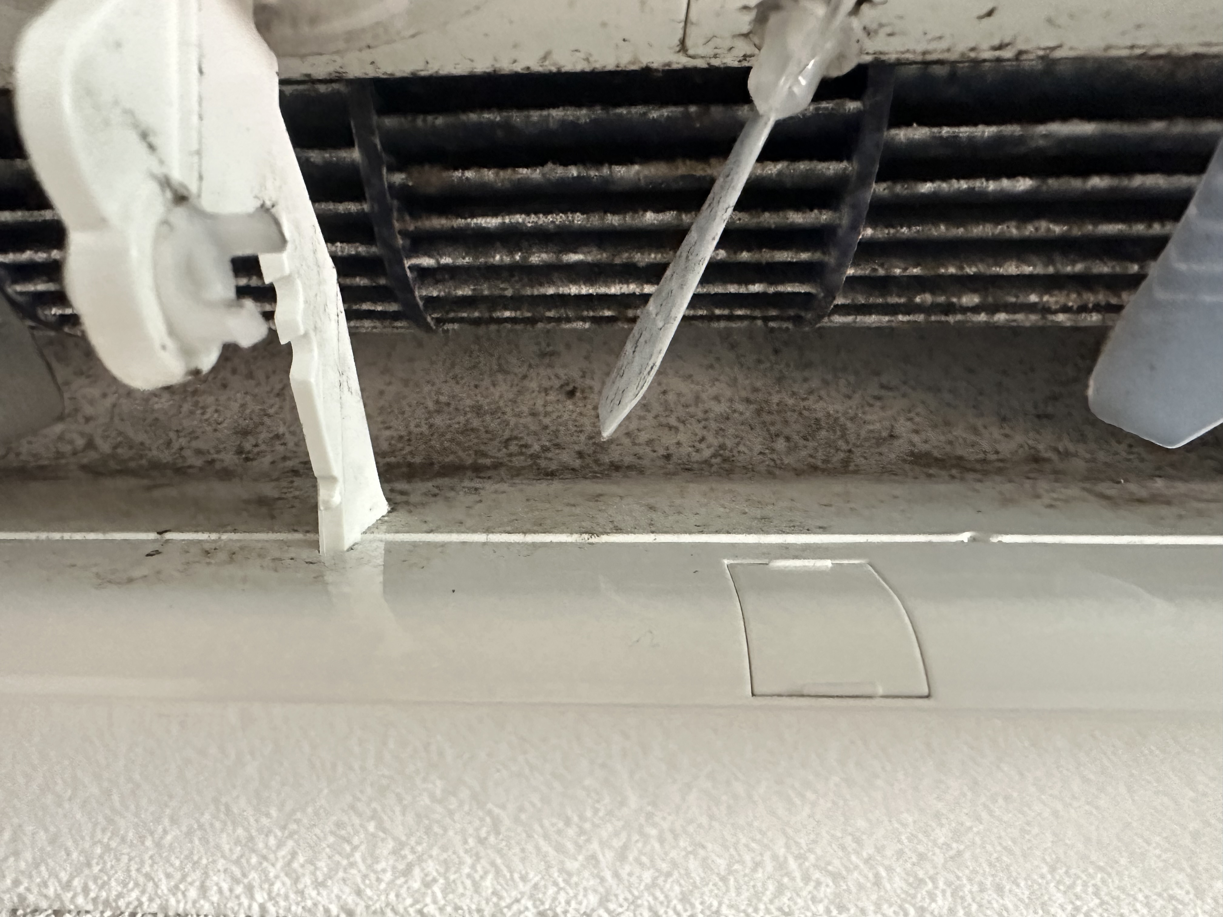 Close-up Carrier binnenunit verdamper met zwarte schimmel- en fijnstofaanslag tussen de lamellen